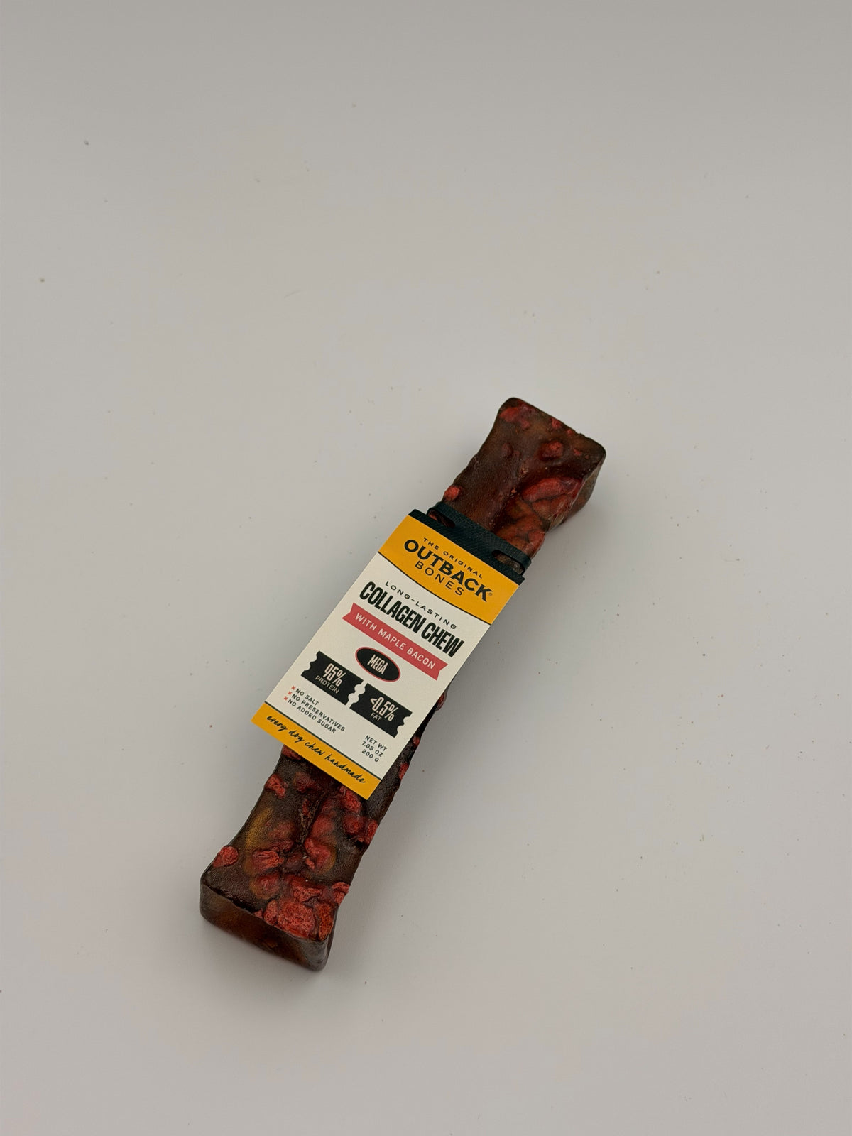 Maple bacon collagen chew lying at an angle with its Outback Bones card tag face-on