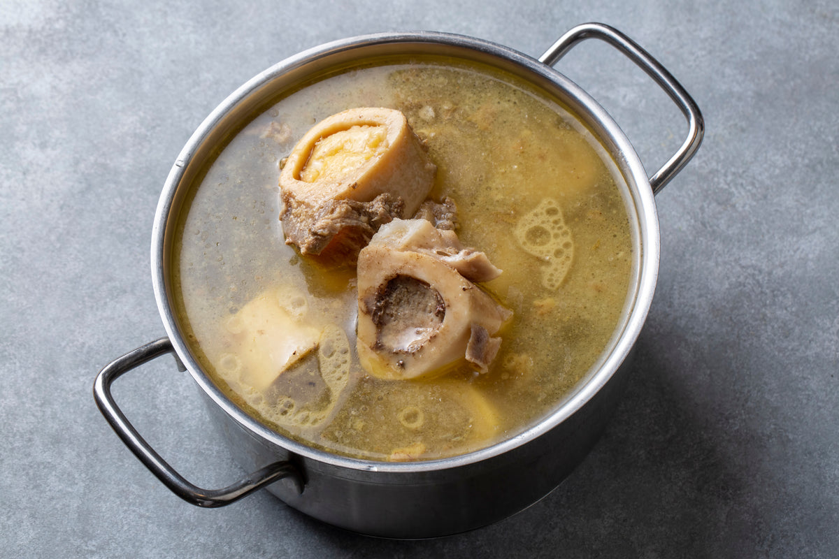 Bone broth simmering in a stockpot with marrow bones